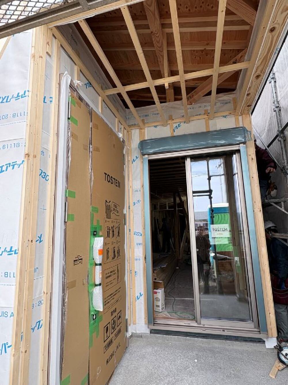 玄関ドアとサッシの設置状況と防水シート施工の様子