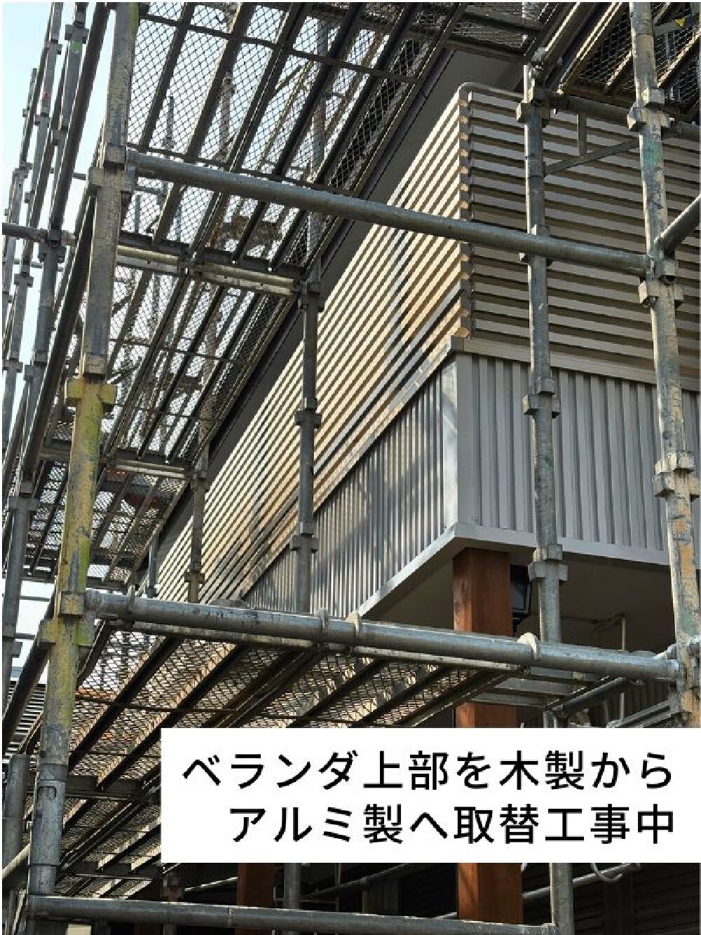 ベランダ上部の木製手すりをアルミ製へ取り替えている工事中の様子。足場を組み、安全に作業を進行中。