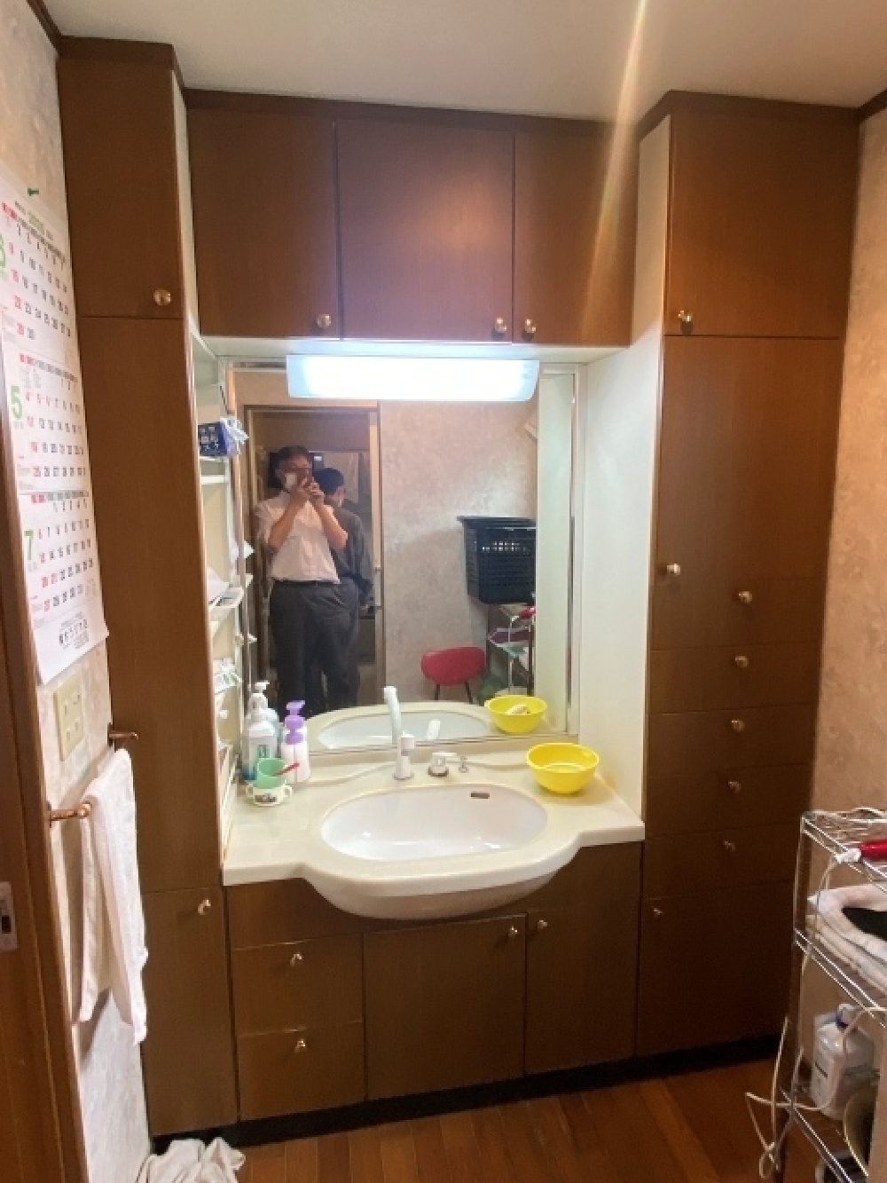 北方町H様邸のリフォーム前洗面所。壁面収納が多いものの使い勝手が悪く、床にワゴンを置いて不足分を補っていた様子。