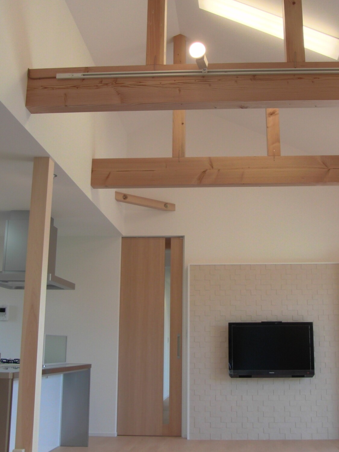 平屋住宅の吹き抜けLDK 大きな梁とテレビ壁が印象的なリビング空間